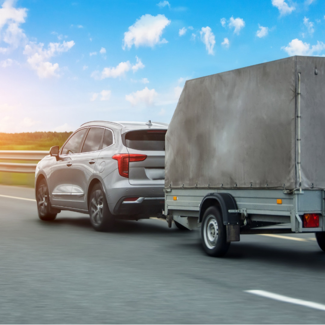 Car towing a grey covered trailer
