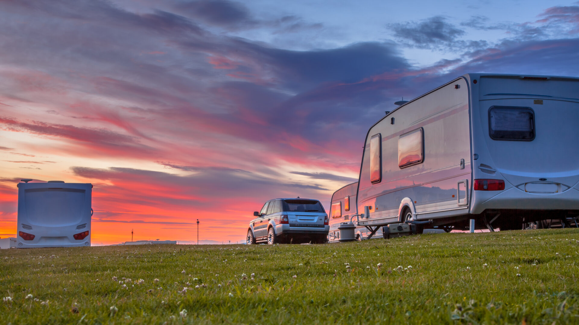 Camping,Caravans,And,Cars,Parked,On,A,Grassy,Campground,Under