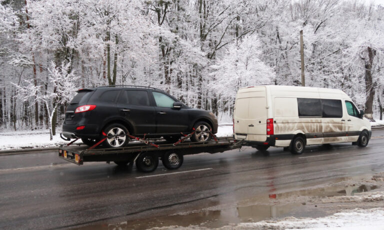 Van towing car trailer in winter snow